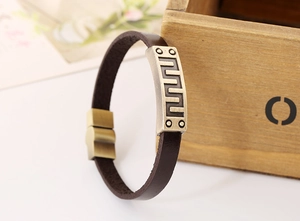 Detailed macro view of retro brown leather bracelet with geometric meander pattern plaque
