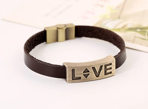Detail of vintage brown leather bracelet with bronze LOVE engraving and magnetic clasp
