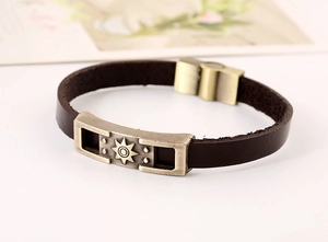Close-up of vintage leather bracelet with bronze sunburst charm and magnetic clasp