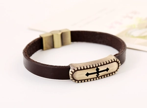 Detail of vintage brown leather bracelet with bronze cross plaque and magnetic clasp