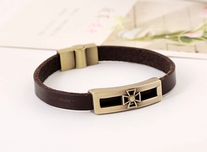 Macro detail of men's leather bracelet with antique bronze cross plate and magnetic clasp