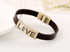 Macro view of vintage brown leather bracelet with bronze LOVE engraving and magnetic clasp