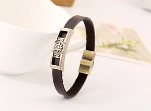 Macro detail of men's leather bracelet with sun motif bronze plate and magnetic buckle