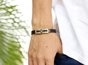 Detail of vintage cowhide bracelet featuring a bronze iron cross plate on man's wrist