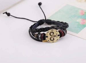 Detalle del signo zodiacal Aries en placa de bronce con pulsera de cuero trenzado multicapa