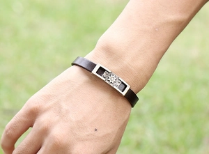 Outdoor shot of men's dark brown leather bracelet with vintage silver sun star motif