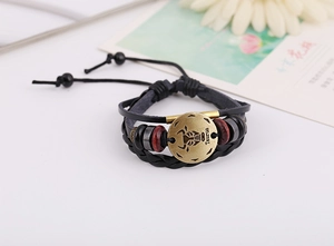 Macro view of bronze Taurus zodiac charm on black multilayer leather punk bracelet