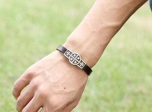 Primo piano di un bracciale in pelle punk con fibbia in argento a croce e teschio al polso