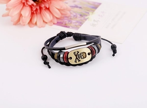 Detail of retro punk leather bracelet with bronze skull charm and multi-layered beads