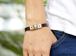 Detail of punk leather bracelet with vintage metal skull and cross on a male wrist