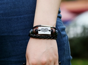 Detail of vintage layered leather bracelet with silver LOVE metal plate and wood beads