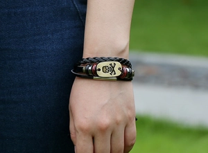 Detail of layered leather bracelet with bronze skull charm and beads on a wrist