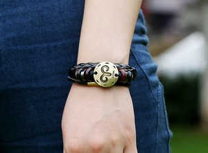 Detalle macro de la pulsera de cuero trenzado Aries con amuleto de bronce en la muñeca