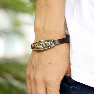 Vintage brown leather wristband with bronze feather metal charm for men worn on wrist