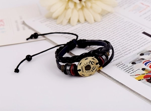 Detail of Cancer zodiac braided leather bracelet with bronze charms on lifestyle background
