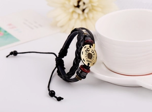 Detail of Cancer constellation leather bracelet with bronze charm on a coffee cup