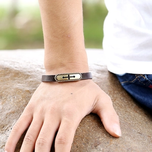 Vintage leather bracelet with cross pendant on model wrist against stone background