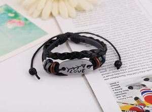 Detail of vintage braided leather bracelet with LOVE engraved metal plate and wooden beads