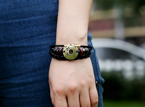Detail of multi-layer leather bracelet with bronze Cancer zodiac sign charm and text