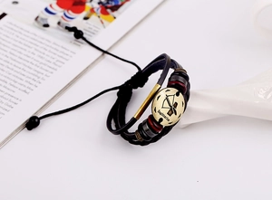 Detailed macro view of Sagittarius zodiac charm on a vintage leather braided bracelet