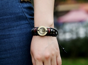 Detail of Yin Yang bronze disc on layered leather bracelet with red wooden beads