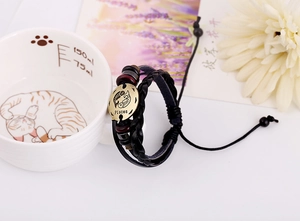 Close-up of Pisces constellation leather bracelet leaning on a decorative ceramic cup