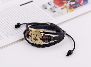 Close-up of Sagittarius zodiac bronze charm on layered braided leather bracelet