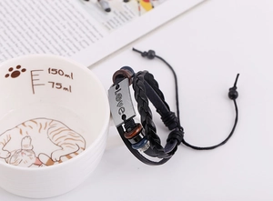 Close-up of multilayer leather bracelet with Love charms on a white cup edge