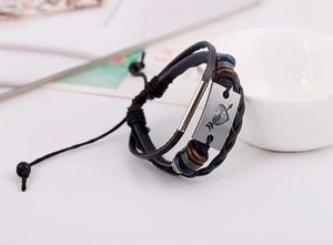 Détail d'un bracelet en cuir tressé noir vintage avec plaque en métal flèche coeur