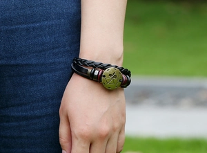 Detail of a vintage layered leather bracelet with a bronze Sagittarius charm on wrist