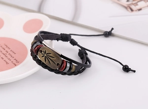 Makroaufnahme von Vintage-Lederarmband mit bronzenem Ahornblatt-Anhänger und Holzperlen