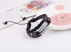 Detail of multi-layer braided leather bracelet with engraved LOVE metal plate and beads
