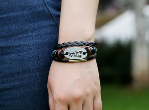 Close-up of multilayer leather bracelet with LOVE engraved metal plate and wooden beads