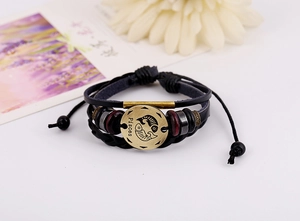 Detail of Pisces constellation charm on braided leather bracelet with wooden beads