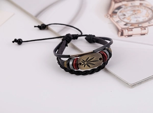 Nahaufnahme eines mehrlagigen Lederarmbands mit Bronze-Blatt-Plakette und Perlen-Details