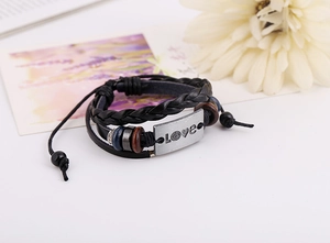 Macro shot of layered leather bracelet with Love metal plate and wooden beads