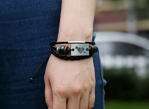 Détail d'un bracelet en cuir multicouche avec plaque en métal flèche-cœur au poignet