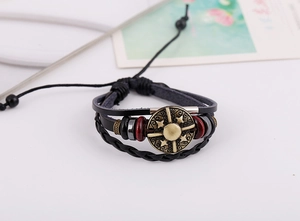 Detail of multi-layer leather bracelet with bronze sun compass charm and braided cords