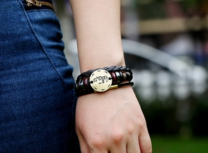 Detail of multi-layer leather bracelet with Virgo zodiac charm on a person's wrist