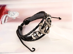 Macro shot of multi-layer braided leather bracelet with vintage silver anchor charm