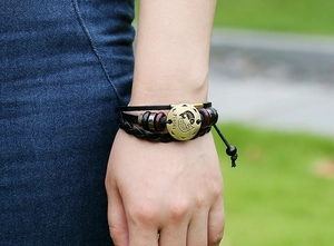 Outdoor shot of Pisces leather bracelet with bronze zodiac charm and braided straps