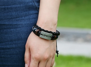 Detail of braided leather bracelet with LOVE metal plate and beads on a model wrist
