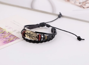 Detail eines mehrlagigen Lederarmbands mit Bronze-Blattanhänger und Holzperlen