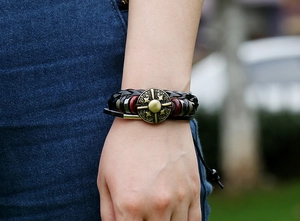 Detail of a punk style layered leather bracelet featuring bronze charms on a male wrist