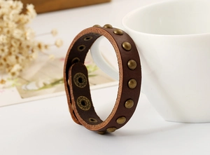 Detailed macro view of dark brown punk leather bracelet with bronze metal rivets and studs