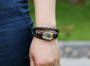 Detailansicht eines mehrlagigen Lederarmbands mit Bronze-Blattanhänger und Holzperlen
