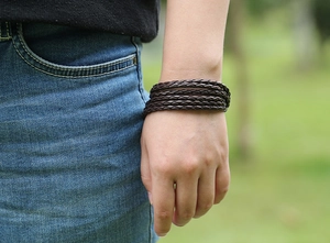 Close-up of a dark brown multi-layer braided leather bracelet on a model wrist