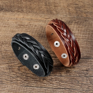 Handmade multilayer braided leather bracelet with retro metal snaps on wood background