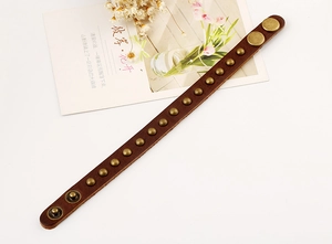 Detail of vintage brown leather punk bracelet with bronze rivets and snap button closure