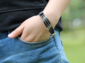 Close-up of a triple-layer black leather bracelet with silver metal bars on a wrist